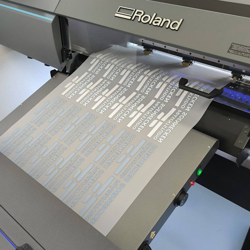 Moderne Druckmaschine von Roland bei der Produktion von Präsentstudio Soennecken, auf der Bögen mit Logos und Schriftzügen des Unternehmens gedruckt werden